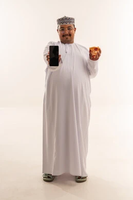 رجل عُماني يحمل بيتزا وهاتف ذكي في استوديو