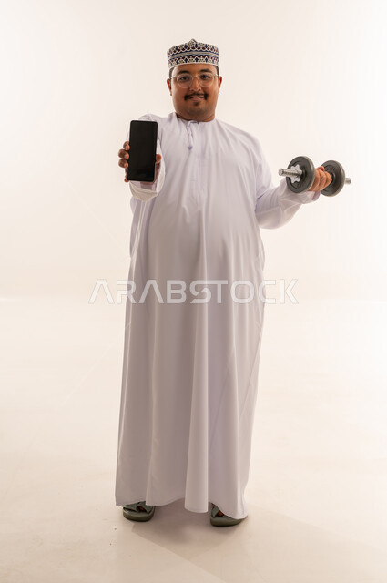Omani Man Holding Smartphone and Dumbbell Studio Shot