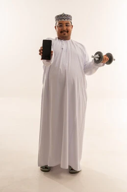 رجل عماني يمسك هاتفاً ودمبل في خلفية بيضاء