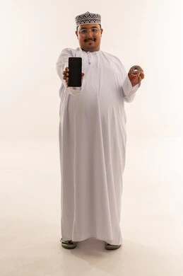 رجل عماني يحمل هاتف ذكي ودونات على خلفية بيضاء