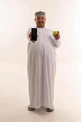 Omani Man Holding Smartphone and Green Apple in Studio
