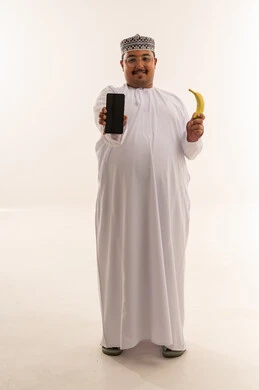 رجل عماني يحمل هاتف ذكي وموزة خلفية بيضاء