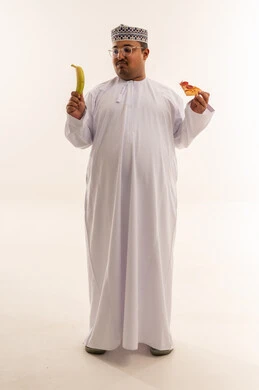 رجل عماني يقارن بين الموز والبيتزا في الاستوديو رجل عماني يقارن بين الموز والبيتزا في الاستوديو