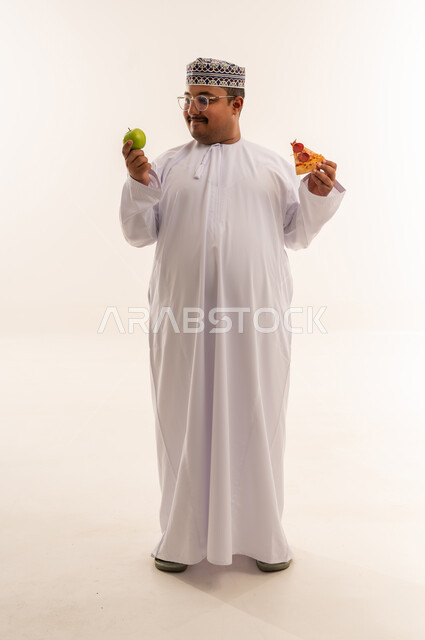 Omani Man Choosing Between Apple and Pizza Studio Shot