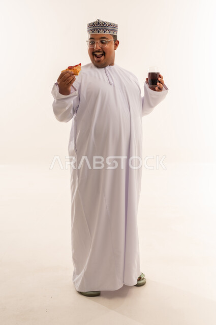رجل عماني يأكل البيتزا مع مشروب غازي خلفية بيضاء