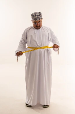 رجل عماني بدين يقيس محيط خصره في الاستوديو