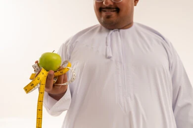 رجل عربي يحمل تفاحة خضراء وشريط قياس