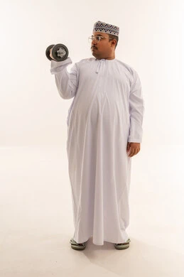 رجل عماني بالزي التقليدي يرفع الأثقال