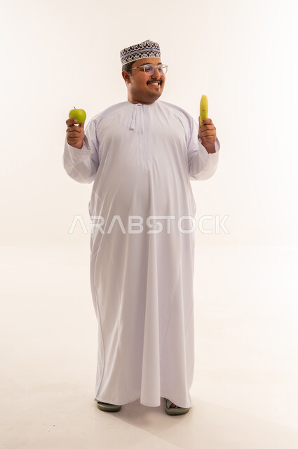 رجل عماني يحمل فاكهة أمام خلفية بيضاء