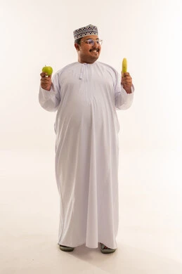 رجل عماني يحمل فاكهة أمام خلفية بيضاء