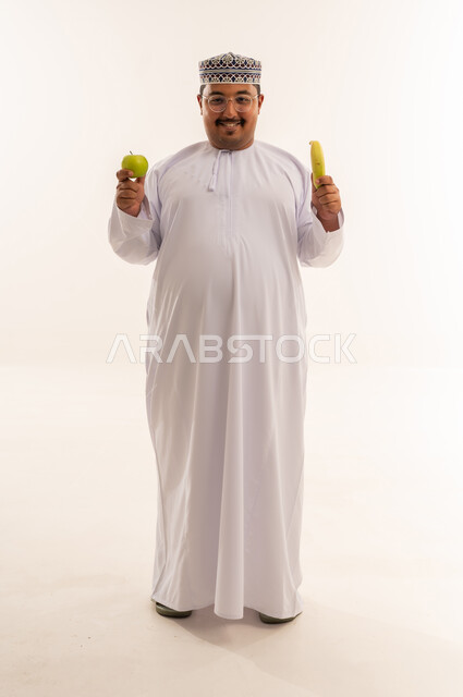 رجل عماني يحمل فاكهة في استوديو خلفية بيضاء