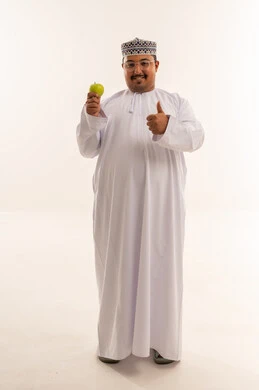 رجل عماني يحمل تفاحة خضراء مع علامة الإعجاب