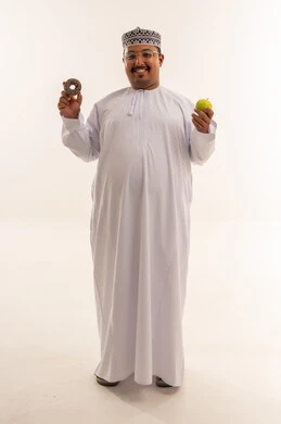 رجل عُماني يختار بين التفاحة الصحية والدونات