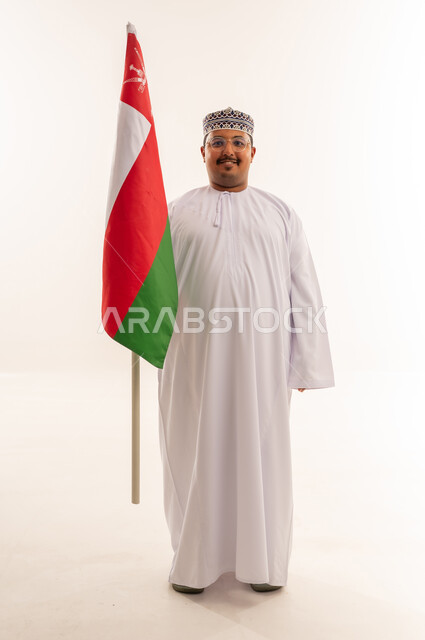 رجل عماني يحمل العلم الوطني بخلفية بيضاء