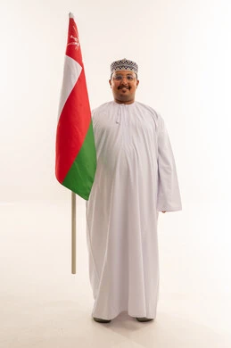 رجل عماني يحمل العلم الوطني بخلفية بيضاء