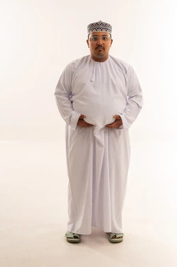 رجل عماني يعاني من السمنة يرتدي دشداشة بخلفية بيضاء