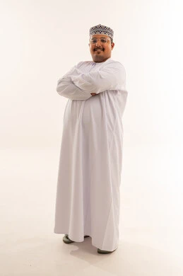 رجل عُماني يرتدي الدشداشة والكمة التقليدية بخلفية بيضاء