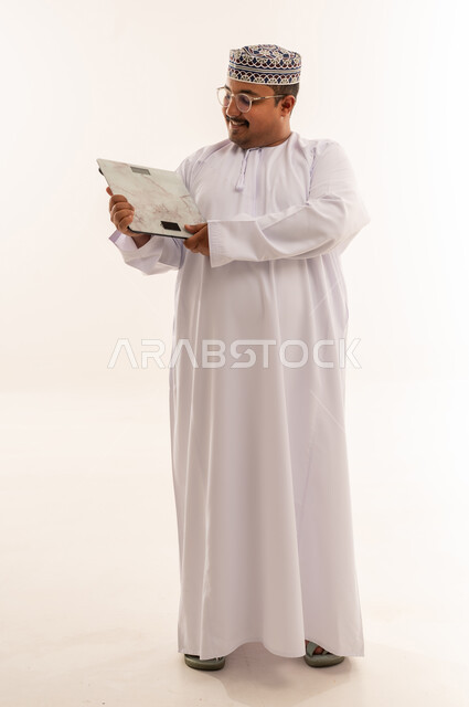 رجل عماني يحمل ميزان وزن في الاستوديو