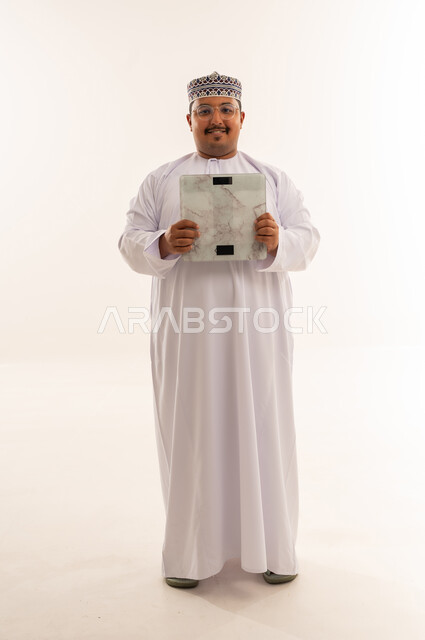 رجل عماني يحمل ميزان قياس وزن في الاستوديو