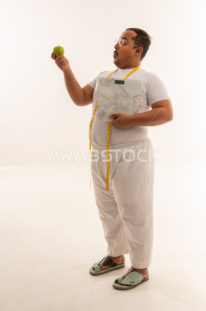 رجل عربي بدين يحمل تفاحة وميزان وزن