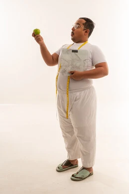 رجل عربي بدين يحمل تفاحة وميزان وزن