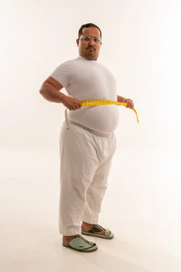 رجل سعودي يعاني من السمنة يقيس خصره في الاستوديو