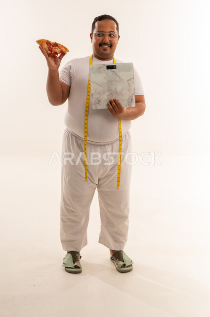 رجل سعودي سمين مع بيتزا وميزان قياس الوزن