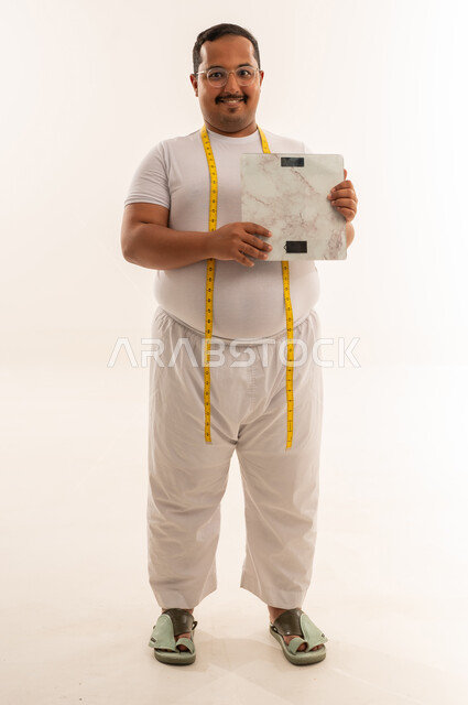 رجل سعودي يعاني من السمنة يحمل ميزان وزن