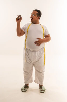 رجل سعودي يعاني من السمنة مع دونات وشريط قياس