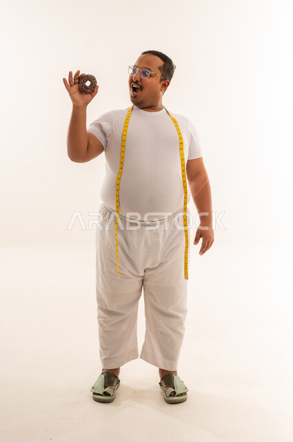 رجل سعودي يعاني من السمنة يحمل دونات