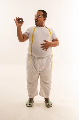 رجل سعودي يعاني من السمنة مع الدونات وشريط قياس