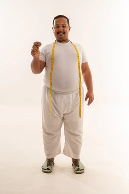 رجل سعودي بدين يحمل قطعة دونات مع شريط قياس