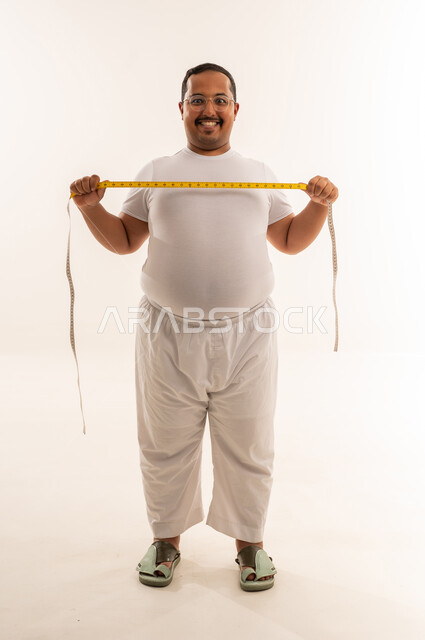 رجل سعودي بدين مع شريط قياس في الاستوديو