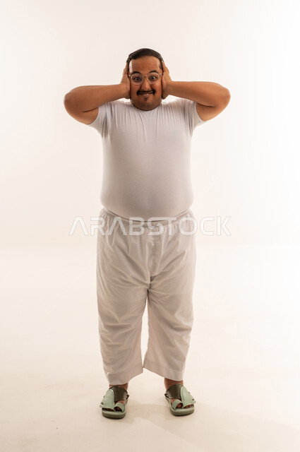 رجل سعودي يغطي أذنيه على خلفية بيضاء