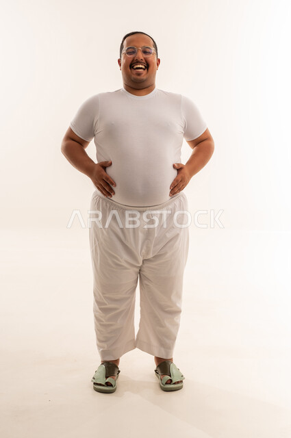 رجل سعودي بدين يضحك في استوديو بخلفية بيضاء