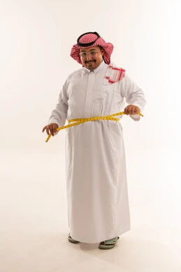 رجل سعودي يعاني من السمنة يقيس خصره في الاستوديو