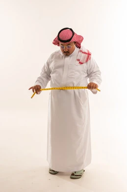 رجل سعودي بدين يقيس خصره في استوديو أبيض