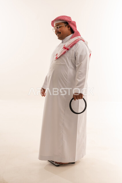 رجل سعودي بدين يقف على ميزان في استوديو