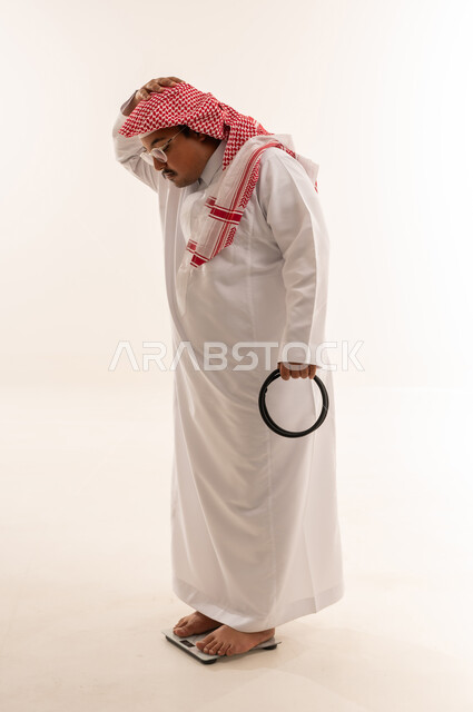 رجل سعودي سمين على ميزان قياس الوزن في الاستوديو