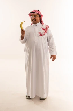 رجل سعودي بدين يمسك موزة في الاستوديو