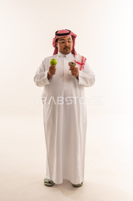 رجل سعودي يختار بين التفاحة والدونات خلفية بيضاء