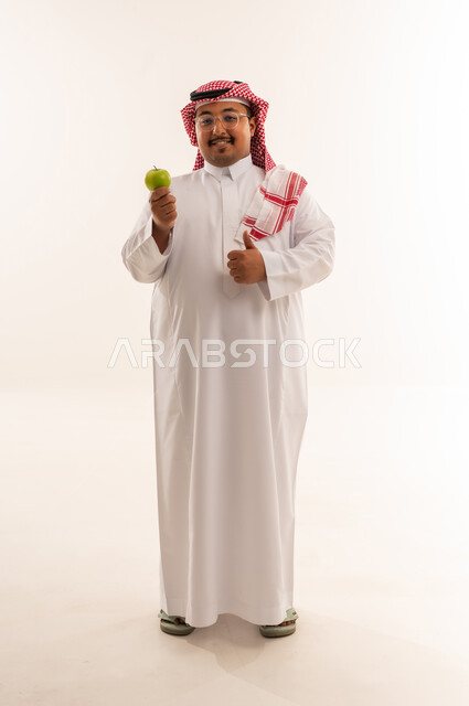 رجل سعودي يحمل تفاحة خضراء في الاستوديو