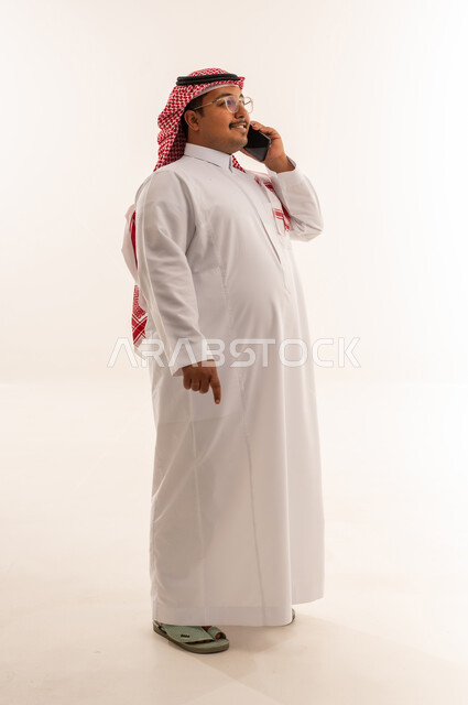 رجل سعودي بالزي التقليدي يستخدم الهاتف الذكي