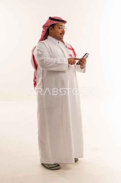 Saudi Man in Traditional Thobe Using Smartphone