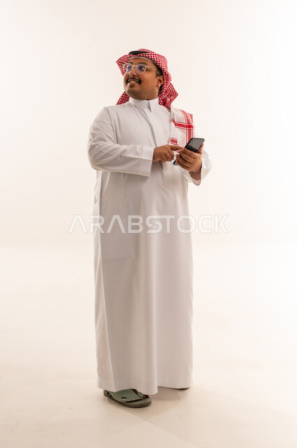 رجل سعودي بالزي التقليدي يستخدم الهاتف الذكي