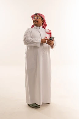 رجل سعودي بالزي التقليدي يستخدم الهاتف الذكي