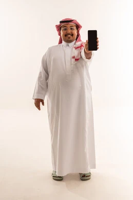 رجل سعودي يحمل هاتف ذكي بخلفية بيضاء