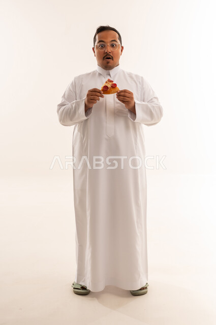 رجل سعودي بوزن زائد مندهش يحمل قطعة بيتزا
