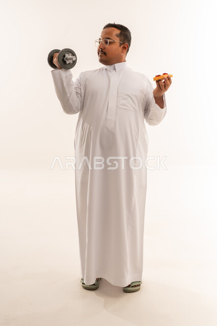 رجل سعودي يحمل دمبل وبيتزا في الاستوديو