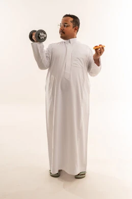 رجل سعودي يحمل دمبل وبيتزا في الاستوديو